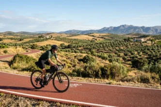 Ciclista recorriendo el asfalto rojo de la Vía Verde del Tajuña en Madrid